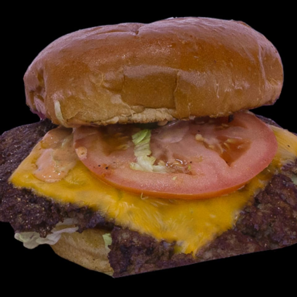 A close-up of a cheeseburger with a beef patty, melted cheese, tomato, lettuce, and sauce.